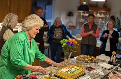 Kathy H, getting the cake ready to cut, with Colleen, Ron, Mary, neighbor Mary and Kathy S in the background