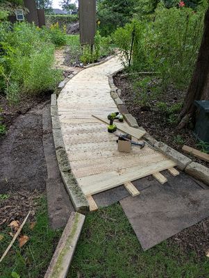 The bare earth area on the left was previously covered by the wider mulch path. After moving the border rocks closer together to make the path narrower, that area will now become more of the back fence flower bed.
I used all my available lumber, but decided I wanted to extend the boardwalk a bit more, so went back to Lowe's to get a few more boards.