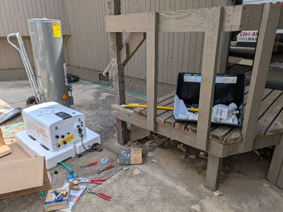 The new tankless heater was larger than we expected, but fit easily into the old space. The black trough to catch any leakage or condensation is on the porch. They replaced the old hot and cold water lines with polyethylene (PEX) tubing.