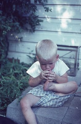 Chris Cordell
196407  Chris trying to put his toe in his mouth on steps on house behind at May?
(date is probably film development date)
