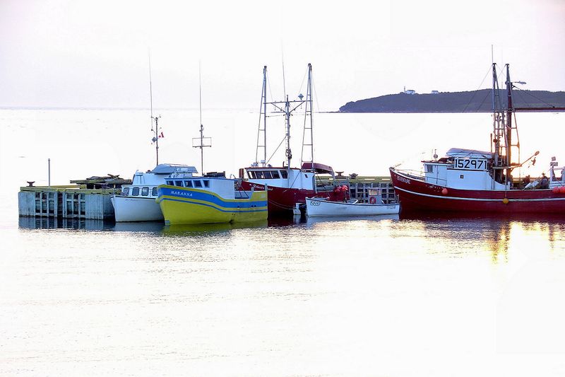 Fishing boats against a bright sunset at Rocky Harbour