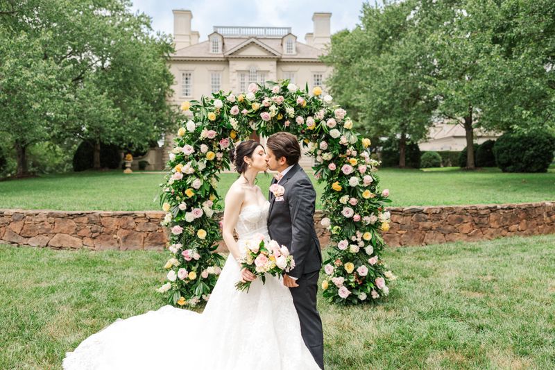 Bride and Groom in front of floral arch ceremony at an estate