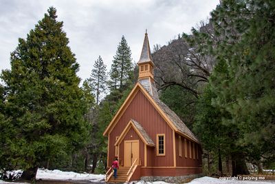 The chapel is dwarfed by the tall trees and rocky mountains around it