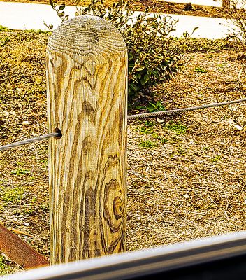 Metal cable through a wooden post.