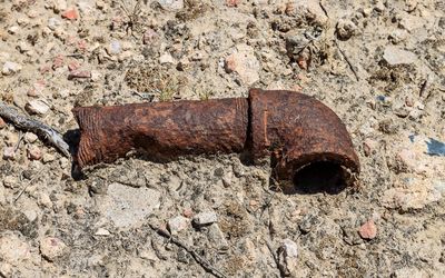 A rusted pipe sits near a foundation in Block 9 L in Amache NHS