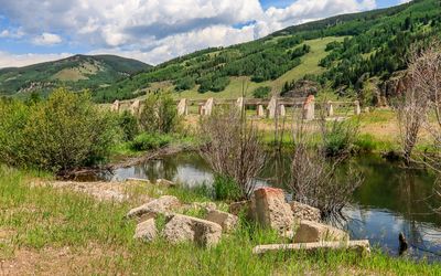 Foundation blocks along the Eagle River with the Field House ruins in the distance in Camp Hale NM