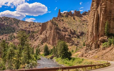 Cliffs and pinnacles rise above US 14 and the Shoshone River in Shoshone National Forest