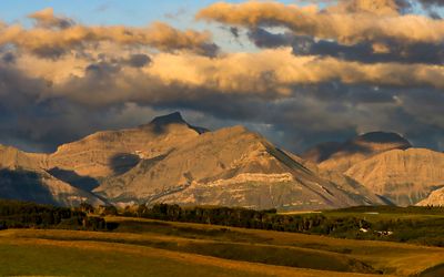 Sunrise bathes the Rocky Mountains and the clouds above in Waterton Lakes NP