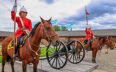 NWMP flank a cannon at the base of the courtyard flag in Fort Macleod