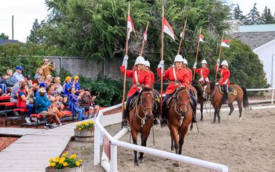 NWMP ride past spectators in pairs in Fort Macleod
