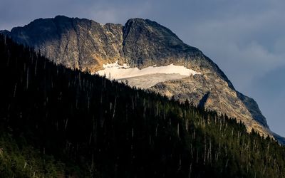 Clouds cast a shadow on the top of a mountain peak in Glacier NP
