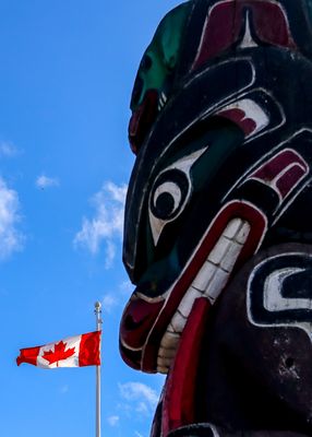 The Canadian flag and a First Nation Totem Pole in Victoria BC