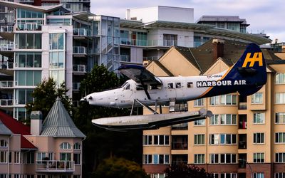 Below the building roof level, a float plane comes in for a landing on Victoria Harbor in Victoria BC