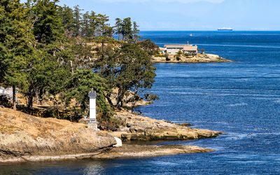 A large ship passes a home on an island point along the Caravan Ferry Crossing Route