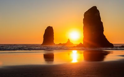 The sun looming large between the Needles before sunset on Cannon Beach