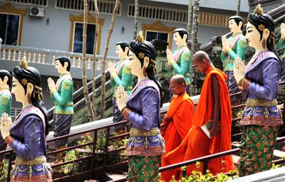 Monks walk down the flight of stairs between rows of statues