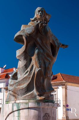 A Princesa Santa Joana nasceu em 1452, filha de D. Afonso V e de sua mulher D. Isabel. Aos três anos de idade ficou órfã de mãe, juntamente com seu irmão recém-nascido, D. João, que viria, mais tarde, a ser cognominado de Príncipe Perfeito. Crescendo num ambiente familiar de instabilidade, de onde surgiram alguns desacertos com seu pai, cedo manifestou o gosto pela vida religiosa. Procurou então refúgio na vida conventual, apesar dos protestos familiares.
Foi Regente do reino na ausência de seu pai, quando este e o seu irmão partiram para o norte de África, em 1471. Em Setembro, do mesmo ano, quando regressaram, D. Afonso V, o Africano, anuiu ao desejo de D. Joana ingressar num convento. Depois da passagem por algumas instituições religiosas, nomeadamente pelos convento de Odivelas e de Santa Clara, em Coimbra, acabou por se decidir pelo Mosteiro de Jesus, na vila de Aveiro. Entrou no referido convento a 04 de agosto de 1472, onde veio a professar em 1475.
Após a morte de seu pai e o nascimento de D. Jorge, fruto de uma relação adulterina de D. João, em 1481, o novo Monarca pediu licença à Santa Sé para que o bastardo fosse confiado a D. Joana, no Mosteiro de Jesus. Quatro anos mais tarde, em 1485, recebeu de seu irmão o “senhorio de Aveiro” com “todas as rendas e direitos reais”, os quais revertiam para seu uso próprio ou do convento. A sua presença ia marcando profundamente a história do próprio Mosteiro e, consequentemente, da então vila de Aveiro.
Faleceu aos trinta e oito anos de idade, no dia 12 de Maio de 1490, data, que séculos mais tarde, se tornou feriado municipal na cidade.
Excertos do artigo publicado em https://www.cm-aveiro.pt/visitantes/arte-publica/estatuas-e-bustos/poi/santa-joana-aveiro