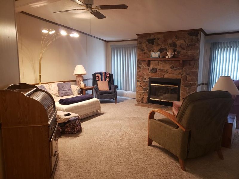 Standing in dining area, here is your view of the living room with stone fireplace with gas logs.