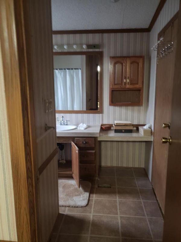 Entry to primary bathroom from next to the bed. Vanity ahead, closet door on right, linen closet is behind this door.