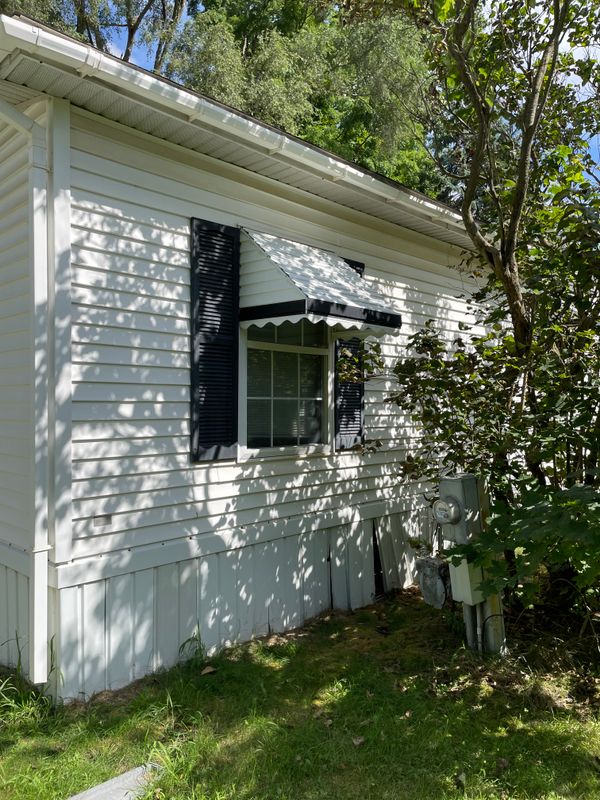 Window of second bedroom with huge lilac tree outside. This side faces the neighboring mobile home.