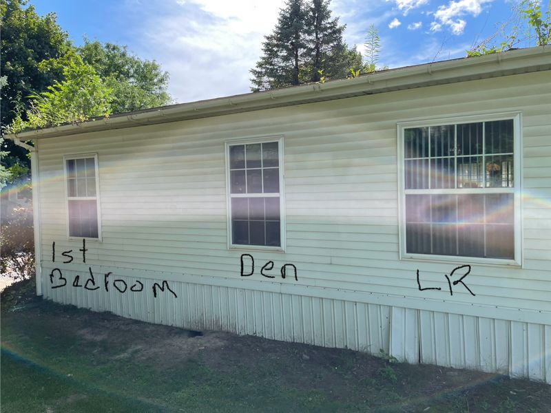 The rest of the long wall facing the hill. Front living room window, den window, and third window of primary bedroom.