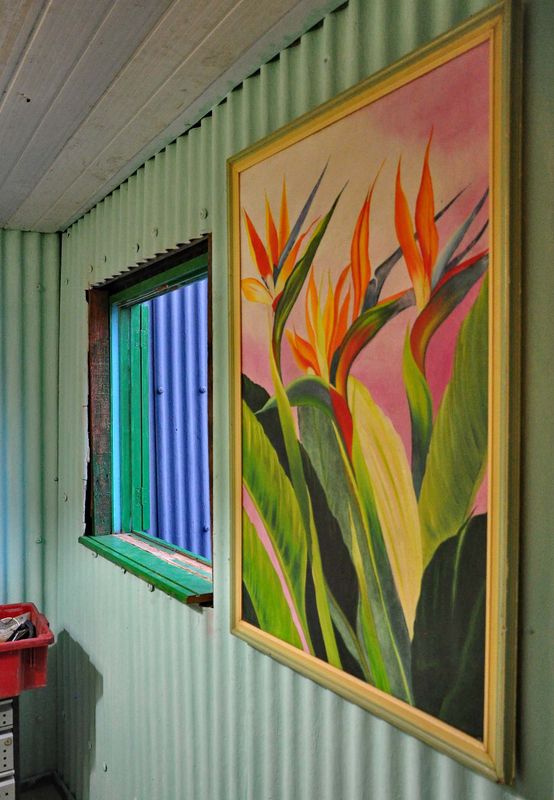 Inside his house; it has been built with discarted materials as the painting on the wall.