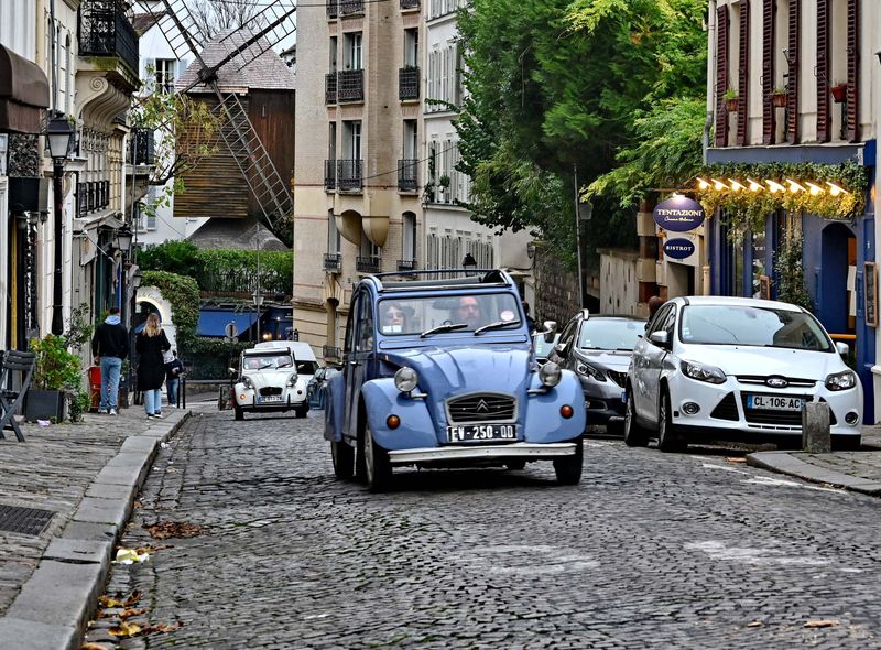 The 2 chevaux Citroen; a typical french car; used for touristic rides; in the background, le Moulin da la Galette.