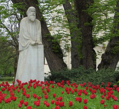 Primoz Trubar Statue with red tulips outside Serbian Orthodox church SS Cyril and Methodius 