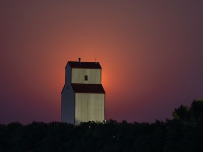 A recent full moon with a country elevator in the foreground.