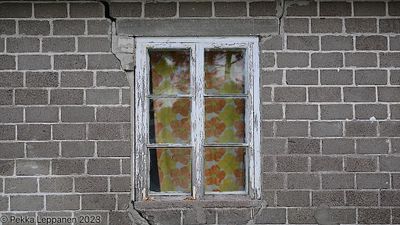 Window with flower curtains in a broken wall