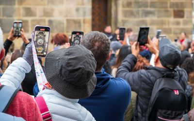 People recording the clock movement as it strikes 12-noon