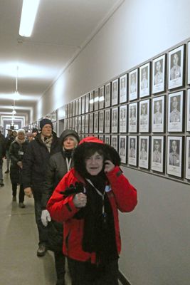 Susan in hall with photos and basic information on Auschwitz prisoners
