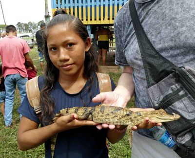 Amazonian girl posing with young Caiman for tips