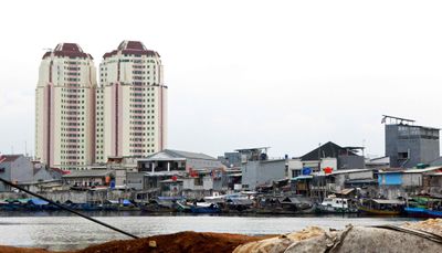 Modern high rises stand behind a historic fishing village in the old port of Jakarta (Sunda Kelapa)