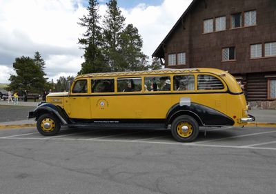 Yellowstone vintage tour bus parked in front of Old Faithful Inn