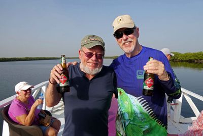 Two veterans starting the day's boat trip with a local beer.JPG