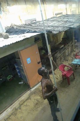 Lifting the electric line off the air conditioning unit on top of our tour bus in Grand Bassam.JPG