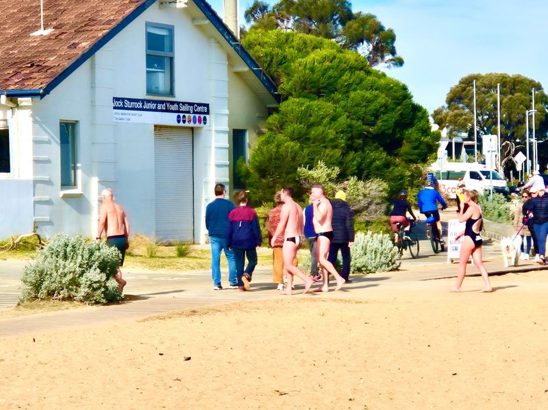 Winter Solstice. Winter swimmers and rugged up walkers at Brighton beach