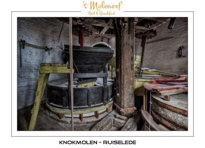 Vertical shaft with spurwheel, cogged pinions and the millstones with wooden casing