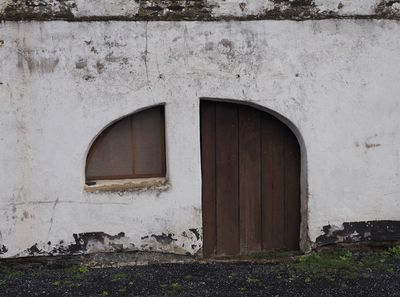 Oddly shaped barn door and window of a derelict farm house