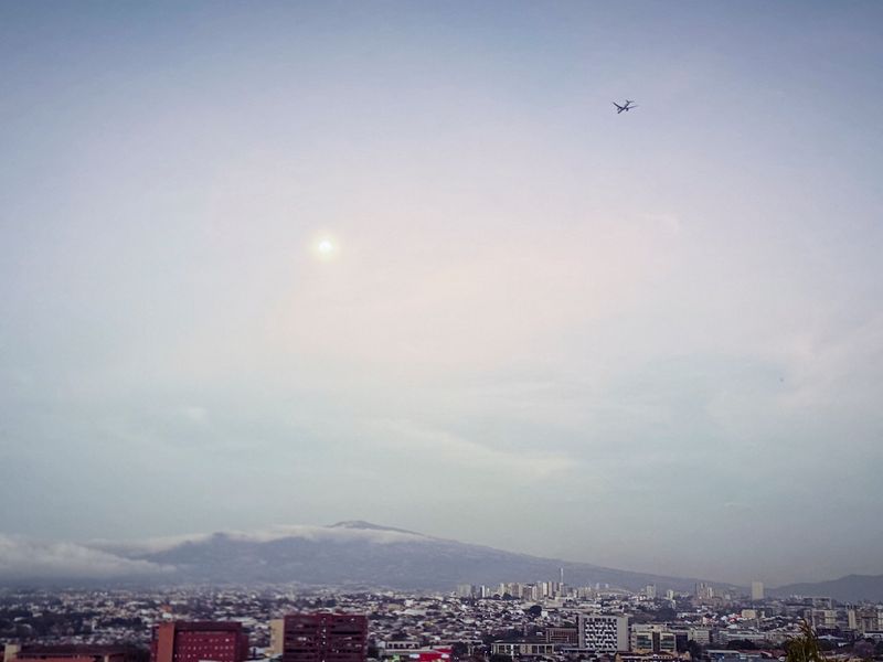 La luna, un avion en ruta al aeropuerto Juan Santamaria, los cerros, y el Paseo de las Palmas.