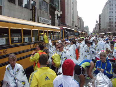 Runners collecting bags from baggage buses after finishing the race