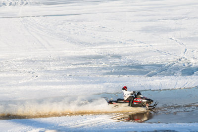 Snowmobile racing along the edge of the Moose River.