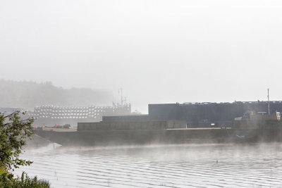 Barges in fog, barge in background with load of pipe