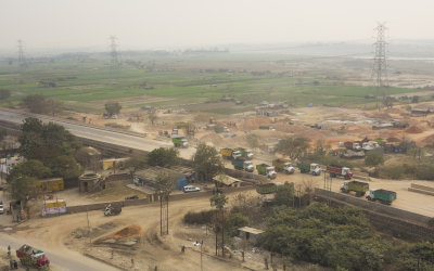 Progress encroaching on the poor (homes/tents in the fields).