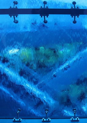 Rulltrappor synliga genom vattenbegjuten hisschaktsglasvägg i Emporia