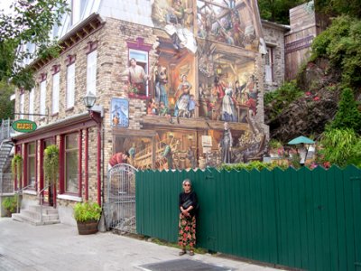 Judy next to a mural on the side of a house on Rue du Petit-Champlain in the Lower Town section of Old Qubec.