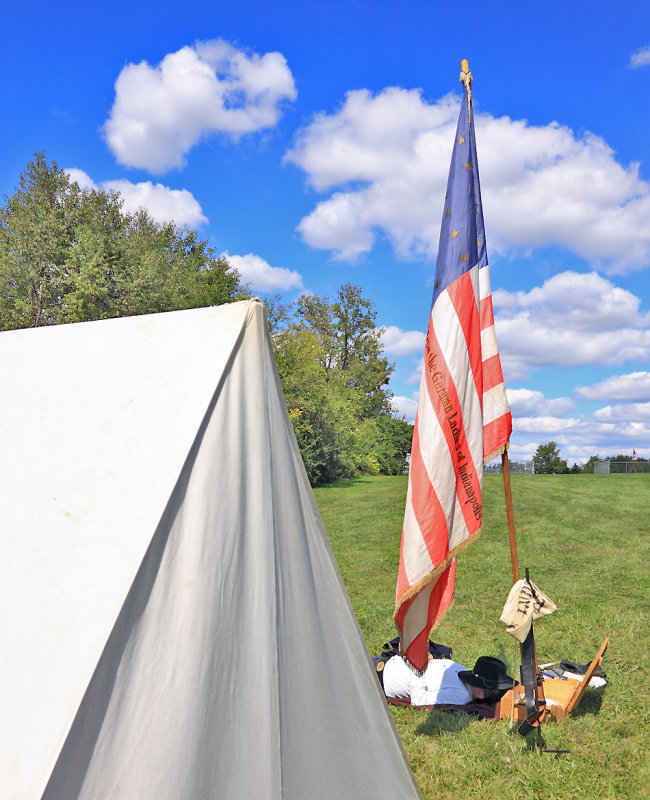 A Union officer catches a nap under the colors. 