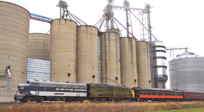 The sound of EMD and ALCO prime movers echo as the train rolls through a valley of grain elevators at Niantic, IL