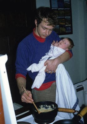 papa cooking with baby steff on his arm